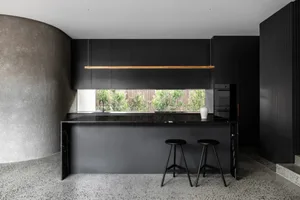 A modern kitchen featuring black marble countertops and sleek black cabinetry.