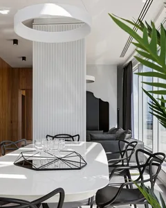 A modern black and white living room with a round dining table, black chairs, and a large window.