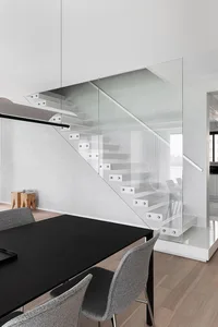 Modern dining room featuring a glass and metal staircase