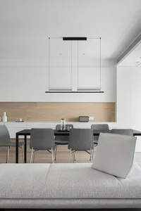 Modern dining room featuring a white minimalist interior design with a sleek dining table, grey chairs, and a hanging light f