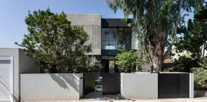 A modern house with a minimalist design, featuring concrete walls and large windows.