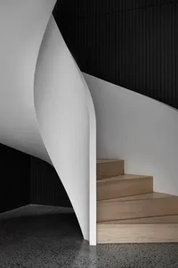 Modern industrial interior with concrete walls and a wooden staircase.