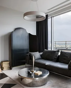 A modern living room featuring a metallic wall art piece and a round, polished metal coffee table.