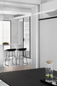 A modern kitchen and dining area with black stools and marble surfaces.