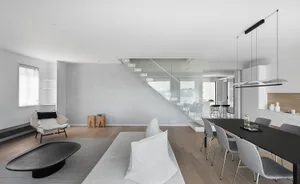Modern minimalist living space featuring a concrete staircase, glass railings, and a contemporary furniture design.