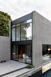 Modern residential house with concrete exterior and large glass windows.