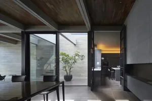 Modern residential kitchen featuring concrete walls, glass windows, and metal fixtures.