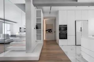 A modern residential kitchen with white tile flooring, wooden cabinets, and a minimalist design.