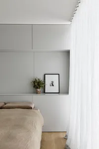 A minimalist bedroom with neutral-toned bedding and a modern, sleek design.