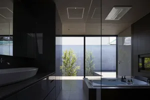 Modern minimalist bathroom with glass walls, concrete floor, and white bathtub.