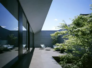 A minimalist residential outdoor space featuring concrete surfaces and greenery.