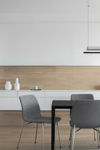 A modern dining room featuring a black table, grey upholstered chairs, and a wooden wall with white floating shelves.