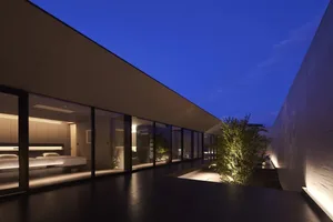 Modern minimalist interior design featuring glass walls and a dark floor.