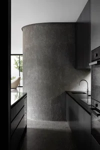 Modern minimalist kitchen featuring gray concrete walls and black cabinetry.