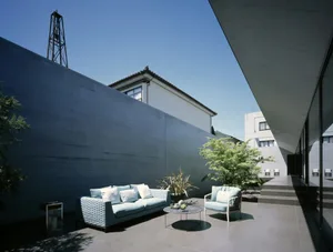 Modern patio with concrete walls, a blue couch, and a circular coffee table.