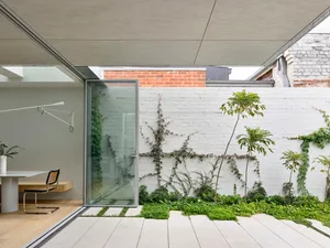 Modern architectural design featuring a white brick wall with concrete flooring and a vine-covered garden.
