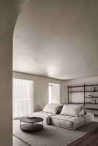 Modern living room with neutral-toned furniture, minimalist design, and a round wooden coffee table.