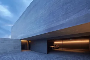 A modern garage constructed of concrete with a single car parked inside.
