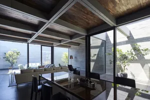 A modern living room with concrete walls, large windows, and a minimalist design.