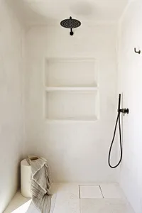 A modern minimalist bathroom with white plaster walls and a rain shower head.