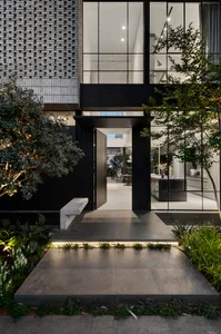 A modern entrance with a concrete floor and black-framed glass doors.