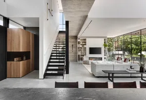 Modern living room with concrete floor, large windows, and minimalist furniture.