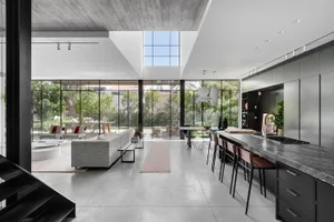 A modern, minimalist residential interior featuring concrete and glass materials.