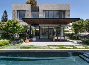 A modern residential exterior featuring concrete materials and a spacious outdoor living area with a pool and garden.