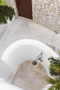 Traditional stone and marble bathroom design with rustic details and a vintage bathtub faucet.