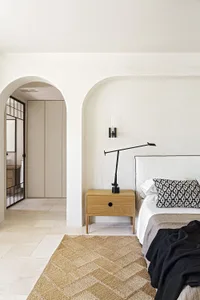 Minimalist bedroom featuring a wooden nightstand, steel headboard, and a rug on the floor.