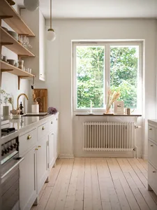 Modern, minimalist residential kitchen with white oak flooring, marble countertops, and open-plan design.