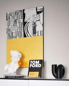 A minimalist interior with a black and yellow abstract artwork, a white bust sculpture, and a book titled 'TOM FORD'.