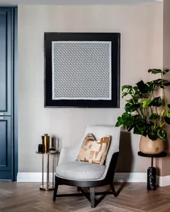 A modern living room with a textile upholstered armchair, a wooden floor, and metallic accents.