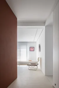 Modern minimalist living space featuring a concrete floor, white walls, and a simple white chair with a pink artwork hanging