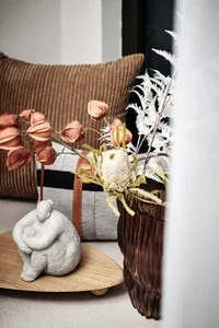 A modern interior setting featuring decorative wooden elements and a vase with white flowers and green leaves.