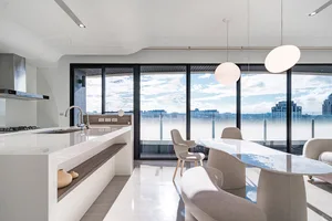 An elegant, modern residential kitchen with a white countertop and glass walls.