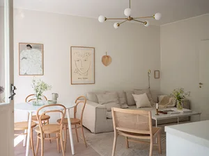 A minimalist living room with a sofa, chairs, and a table in neutral tones.