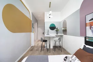 A minimalist bedroom featuring geometric wall art and a low-profile bed with a single decorative pillow.