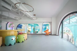 A minimalist playroom with colorful, modern furniture and large windows.