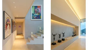 A modern hallway featuring concrete stairs and walls with abstract paintings and sculptures highlighted by subtle lighting.