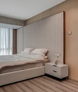 A minimalist bedroom with a textured fabric headboard and beige bedding.