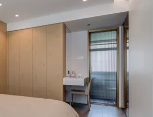 A minimalist bedroom featuring wooden furniture and glass doors, with a wooden bed and a glass-walled closet.