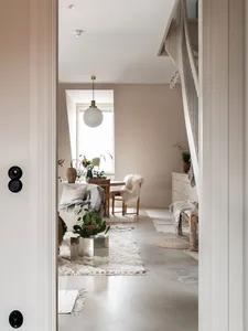 A minimalist living room with a concrete floor, a white sofa, and a wooden dining table.