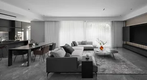 A minimalist living room featuring marble accents, fabric sofas, and a wooden dining table.