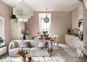 A minimalist living room with neutral tones, featuring a white sofa, white rug, and white walls with a large window.