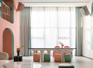 A modern minimalist restaurant with a white acrylic dining table and colorful stools.