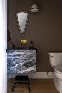 A modern bathroom featuring a marble sink and mirror with a geometric frame.