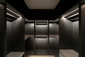 An empty, minimalist closet with concrete walls and shelves illuminated by embedded lighting.