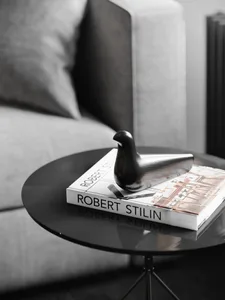 A modern black metal bird decorative figurine placed on top of a coffee table in a living room setting.
