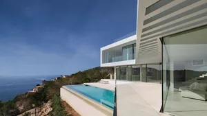 Modern house featuring glass, concrete, and steel exterior with sea view.